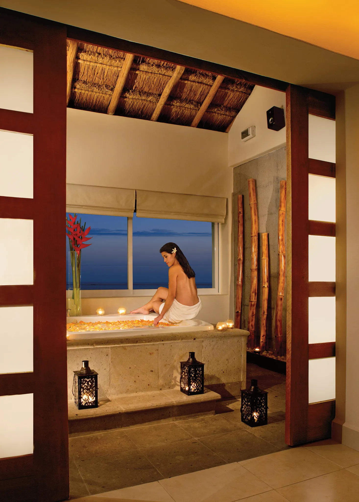 Woman relaxing in a candlelit spa bathtub at Secrets Aura Cozumel, enjoying a tranquil luxury wellness experience with ocean views.