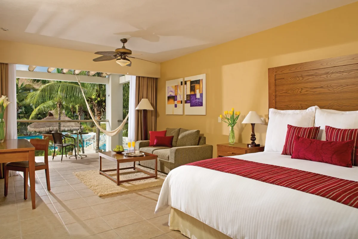 Junior Suite Pool View with king bed, living area, and balcony with hammock at Secrets Aura Cozumel.